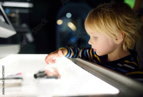 Little caucasian boy is looking an exposition in a scientific museum. Keen child is exploring of exhibits. Education and entertainment for children. Activities for family with kids.