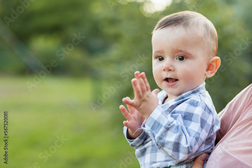 Portrait of happy baby that mother is holding in her arms outdoors. Copy space