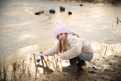 A girl lets paper boats on the shore of a pond © mariyakuprevich