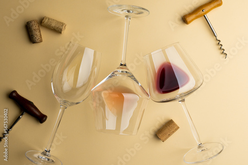 Glasses with red, rose and white wine and corkscrews on yellow background