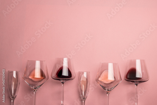 Glasses with red, rose and white wine on pink background, with copy space