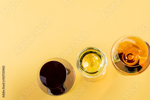 Glasses with red, rose and white wine on yellow background, with copy space