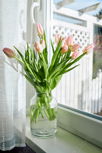 Bouquet of beautiful spring pink tulips in a vase on a windowsill on a sunny day