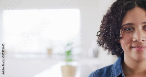 Half face portrait of smiling biracial woman looking to camera with copy space, in slow motion photo