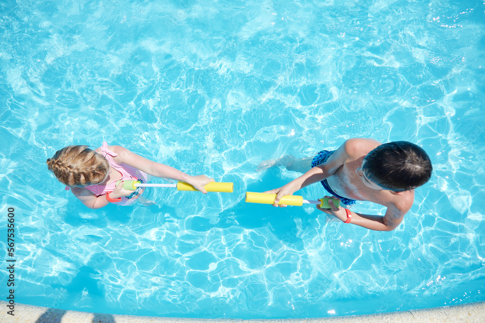 positive children splash water in the pool in summer.