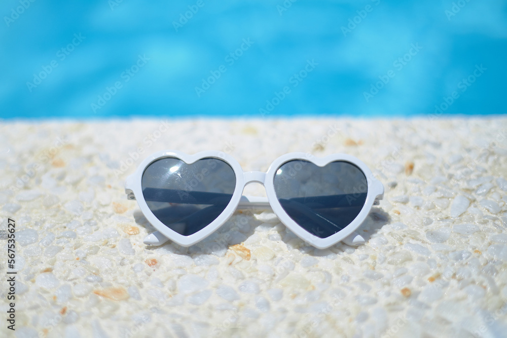 white sunglasses in the shape of a heart. by the pool in a luxury hotel. The concept of summer travel, with children, holidays, holidays and family weekends.