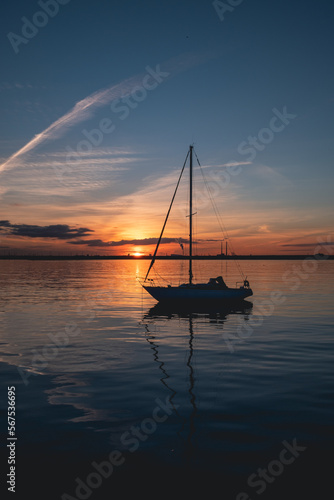 Silhouette of a boat during sunset with energy plant in the background, Dun Laoghaire, Ireland