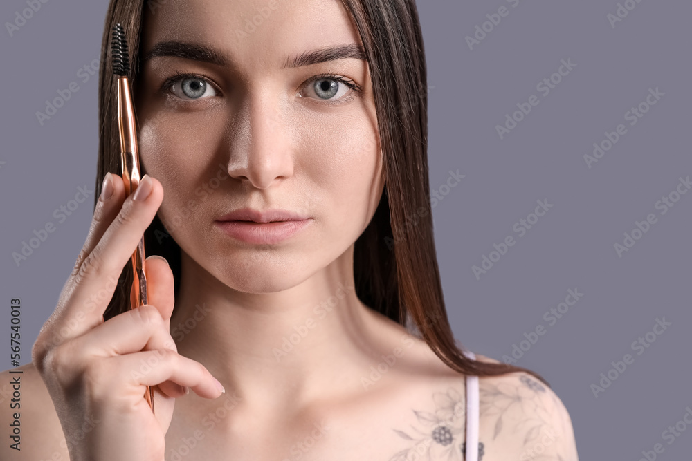 Young woman with brow brush on dark background, closeup Young woman with brow brush on dark background, closeup