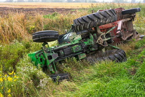 A tractor and cart from a local farm lay in a ditch after rolling off a road in Ontario Canada. photo