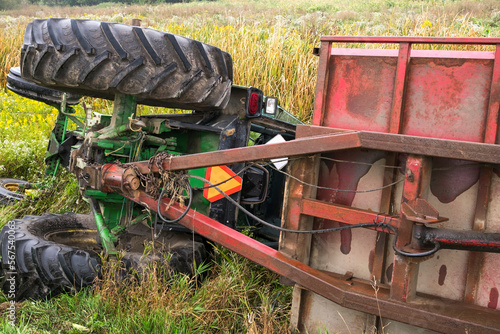 A farm tractor and the attached cart lay on their side in a ditch in rural Ontario Canada.