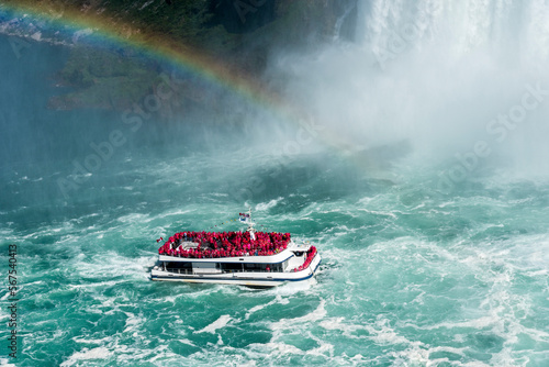 A rainbow guides a tour boat as it plies the turbulent water of the Niagara River on its way to the base of the Horseshoe Falls. Niagara Falls Canada.