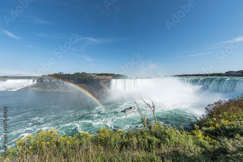 A tour boat at the end of a rainbow takes tourists to the base of the Horseshoe Falls in Niagara Falls Ontario Canada.