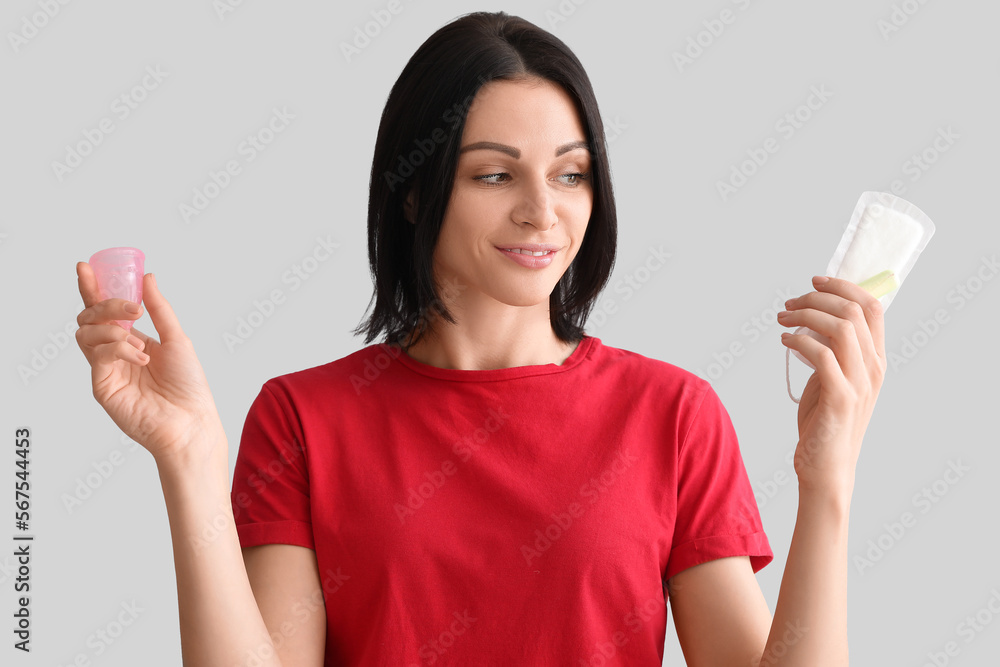 Young woman with menstrual pad, cup and tampon on grey background, closeup Young woman with menstrual pad, cup and tampon on grey background, closeup