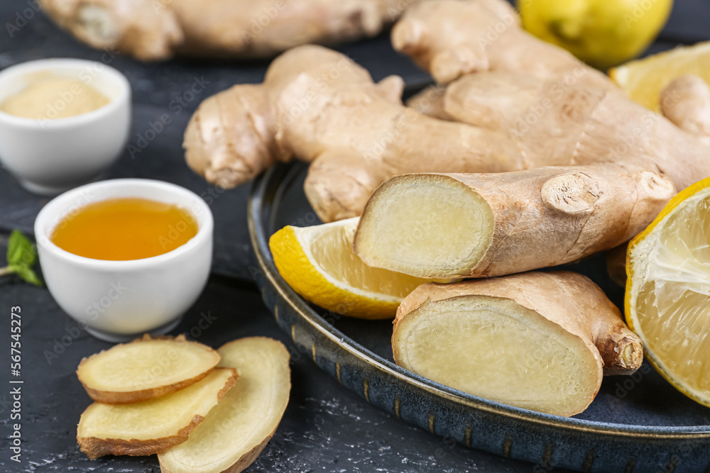 Plate with ginger roots, slices and honey on table, closeup Plate with ginger roots, slices and honey on table, closeup