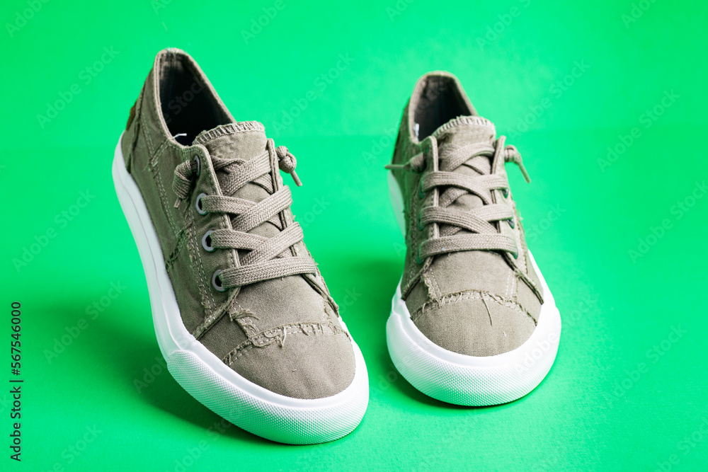 Walking canvas shoes - sneakers. Modern fashionable shoes on a green background close-up.