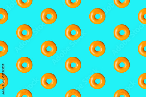 Colorful donut pattern of freshly baked glazed ring doughnuts on a vivid blue background. From top view. Minimal food concept