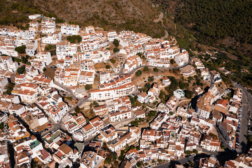 View from drone of picturesque Spanish town of Ojen in green valley surrounded by Sierra Blanca and Sierra Alpujata mountan ranges on sunny fall day, Malaga province