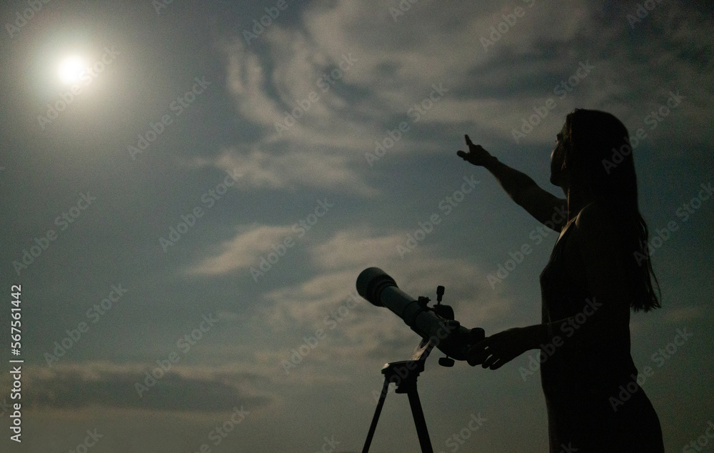 Woman with a telescope looking at the evening sky