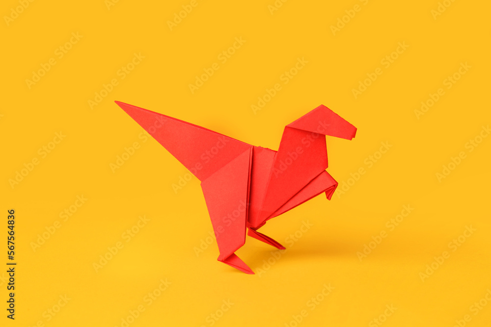 Fototapeta premium Origami art. Handmade red paper dinosaur on yellow background