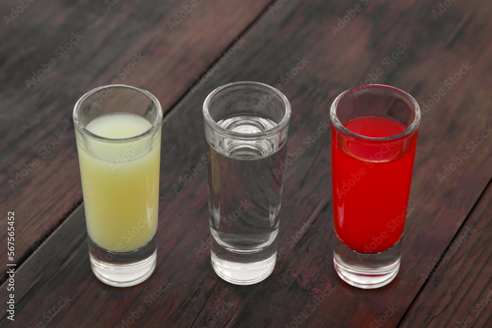 Shots with lime juice, tequila and sangria as colors of mexican flag on wooden table. Traditional serving Shots with lime juice, tequila and sangria as colors of mexican flag on wooden table. Traditional serving