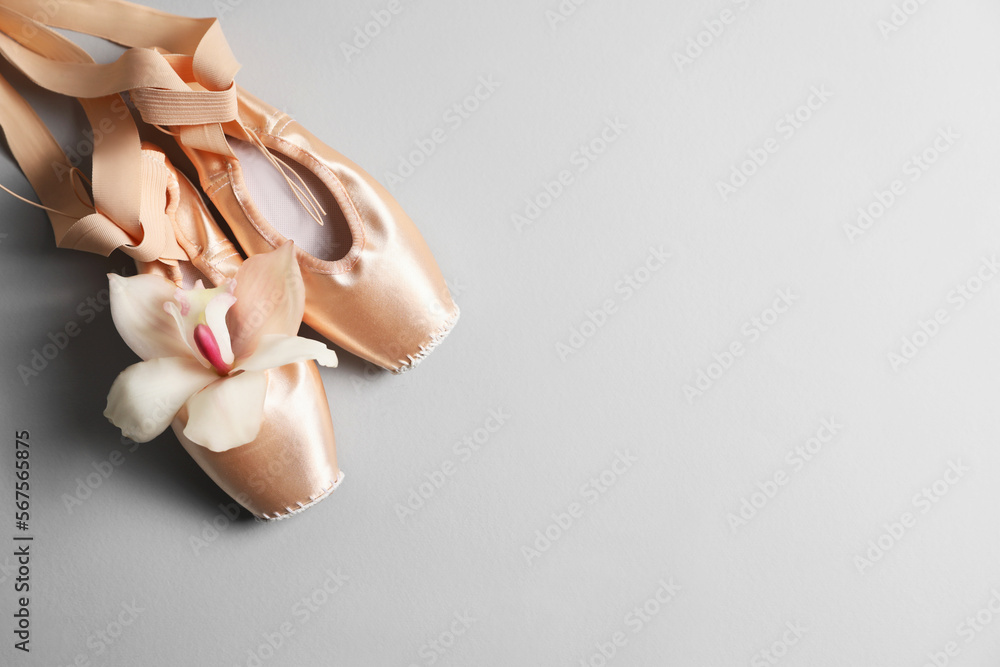 Ballet shoes. Elegant pointes and orchid flower on grey background, flat lay. Space for text Ballet shoes. Elegant pointes and orchid flower on grey background, flat lay. Space for text