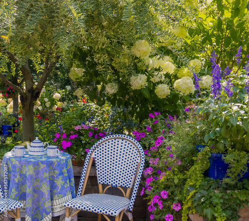 Awash with color this vibrant terrace garden with lush green foliage, chartreuse blooms of limelight hydrangea and complementary violet flowers is the perfect venue for tea.  photo