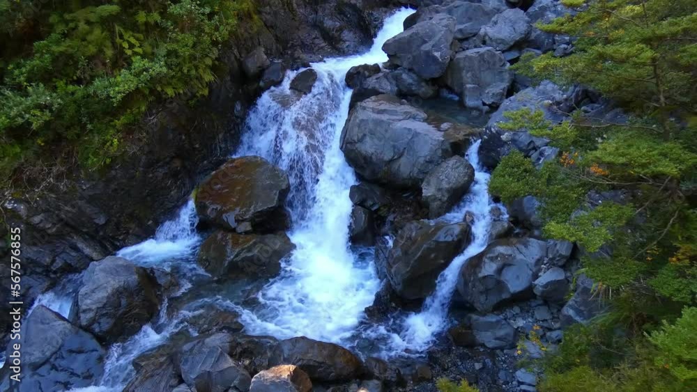 Waterfall creek passing through large rocks in shade of early-morning sunshine - Devil's Punchbowl Waterfall Walk, Arthur's Pass National Park (New Zealand) Waterfall creek passing through large rocks in shade of early-morning sunshine - Devil's Punchbowl Waterfall Walk, Arthur's Pass National Park (New Zealand)
