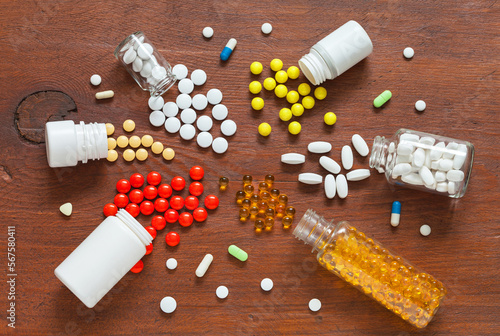 Top view of different types of colorful pills, vitamins, medical drugs, bio supplements, painkillers, antibiotics and fish oil on wooden background. Health care concept. Flat lay, close-up, mock up