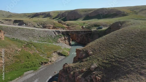 Epic aerial drone shot of an old bridge near the Kel-Suu lake with an SUV driving over it in Kyrgyzstan photo