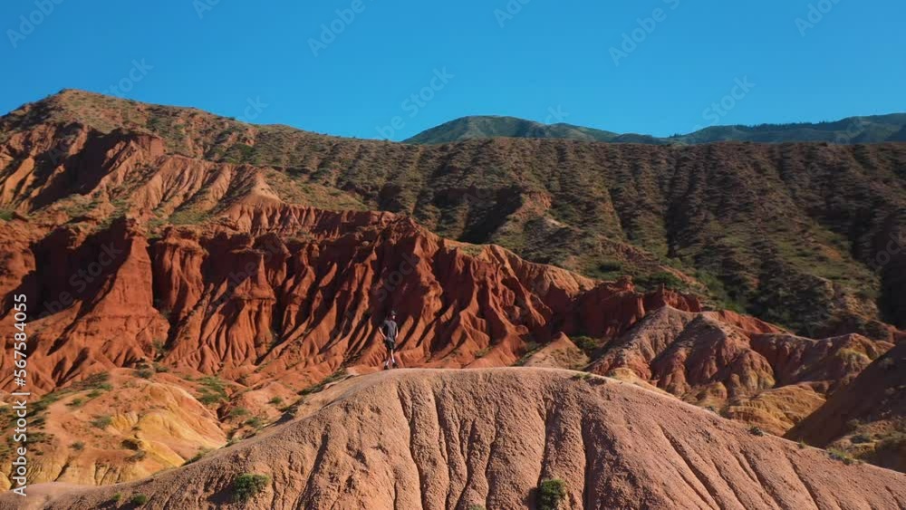 Man standing on canyon ridge at Fairy Tale Canyon near Issyk-Kul Lake in Karakol, Kyrgyzstan, rotating drone shot Man standing on canyon ridge at Fairy Tale Canyon near Issyk-Kul Lake in Karakol, Kyrgyzstan, rotating drone shot