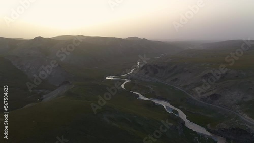 Sun setting over a mountain range in Kyrgyzstan, rotating drone shooting into the sun photo