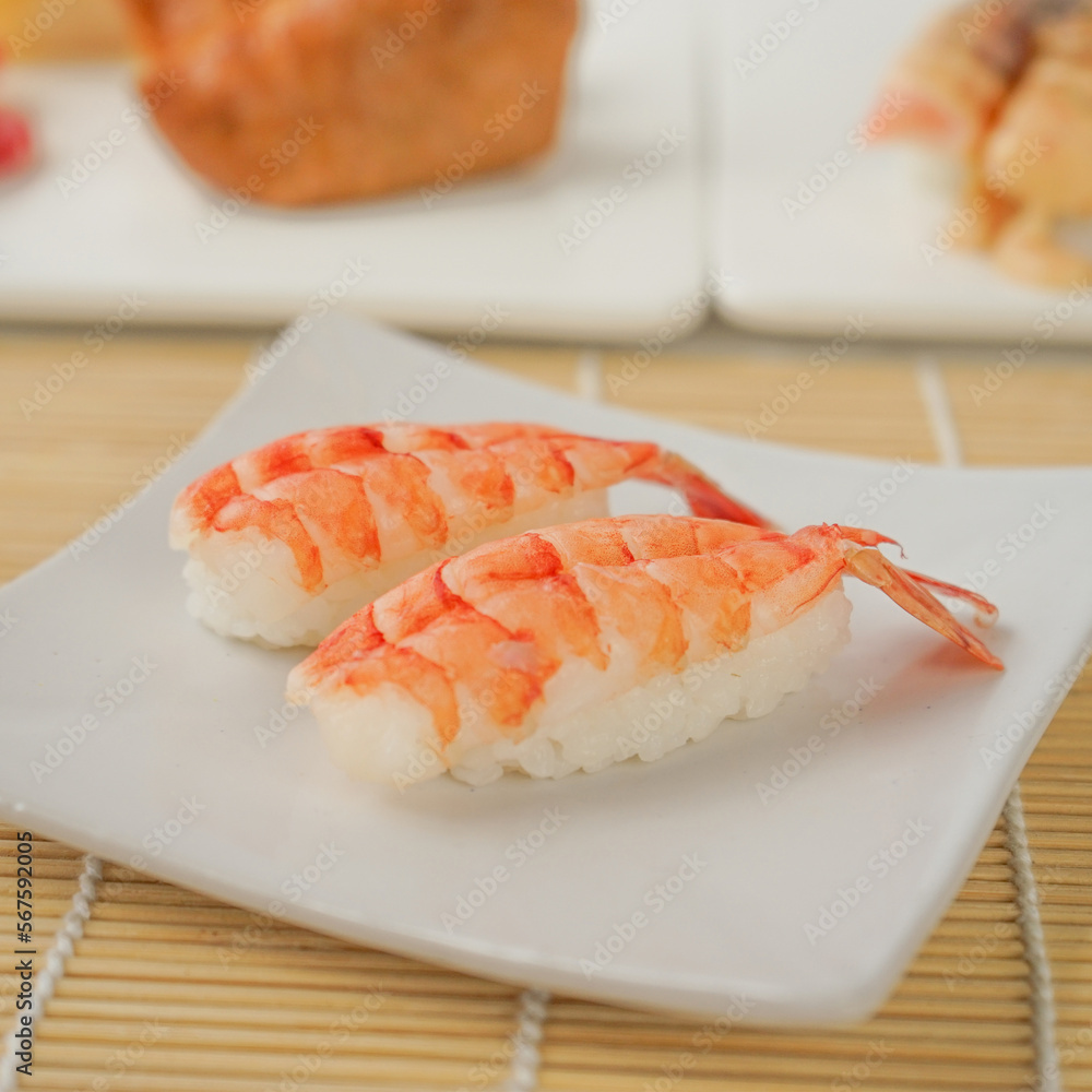 two pieces of sushi with boiled shrimp on top. two pieces of sushi with boiled shrimp on top.