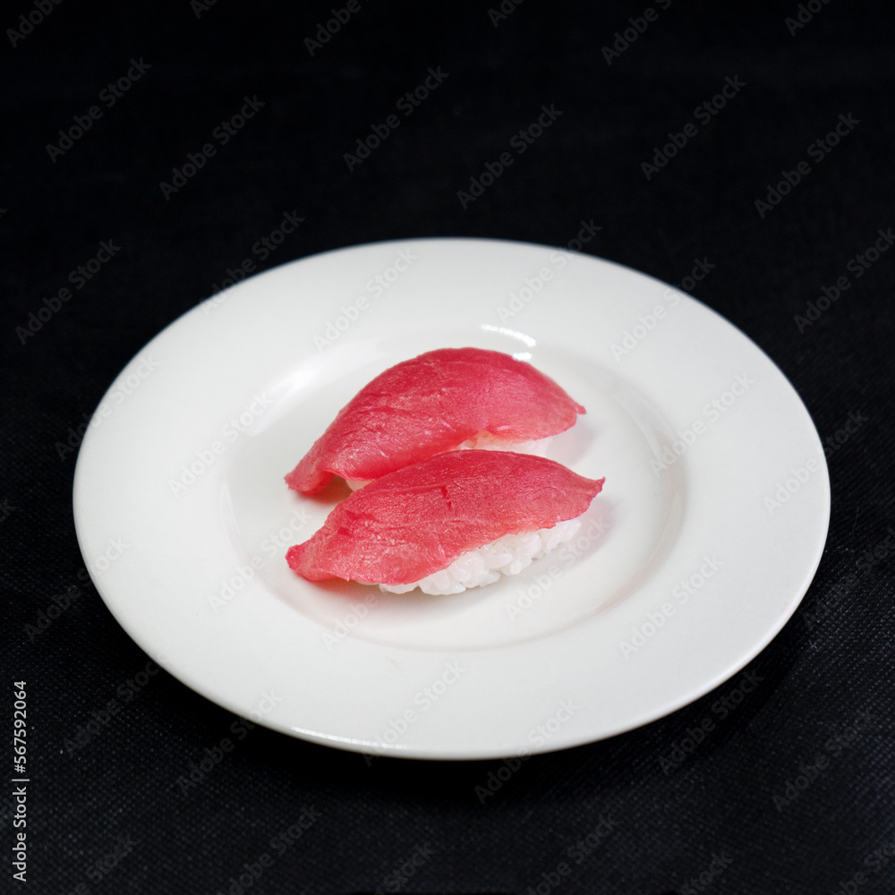 Japanese Sushi - Maguro Nigiri Sushi (Tuna Sushi) on black Background and white plate. Japanese Sushi - Maguro Nigiri Sushi (Tuna Sushi) on black Background and white plate.