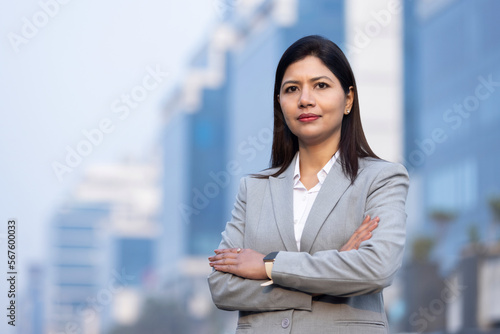 Powerful indian businesswoman leader standing with arm crossed in city office building background