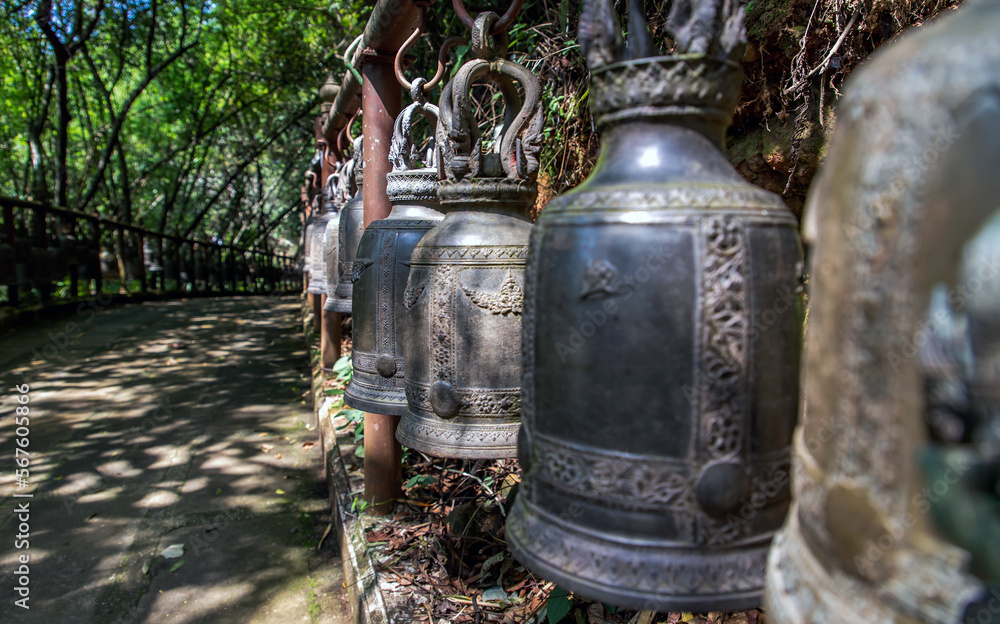 Many metallic bells hanging in a row on wooden pillars outside in thai buddhist temple. Lined with many beautiful bells, Thai temple bell which believe that who knock this bell will get the good luck,