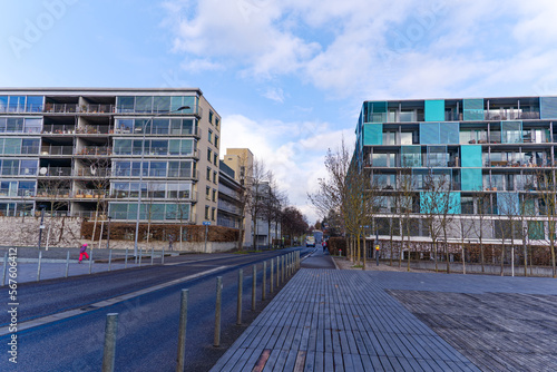 Diminishing perspective of urban road and apartment buildings at public park at City of Zürich district Oerlikon on a blue cloudy winter day. Photo taken January 31st, 2023, Zurich, Switzerland.