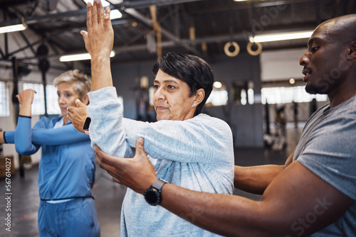 Fitness, personal trainer and senior women stretching before a wellness workout in a training studio. Health, warm up and elderly female friends in retirement doing a exercise with male coach in gym.