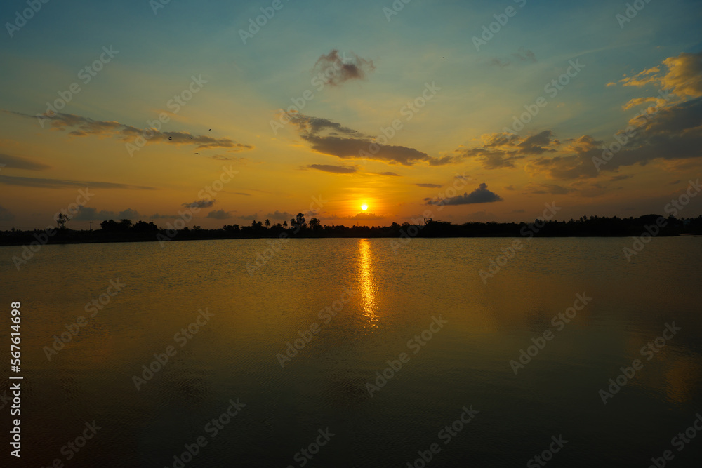 beautiful teal and orange color sunset at the lake on agricultural land in the village