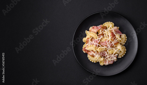 Delicious pasta with bacon and parmesan cheese on a black ceramic plate