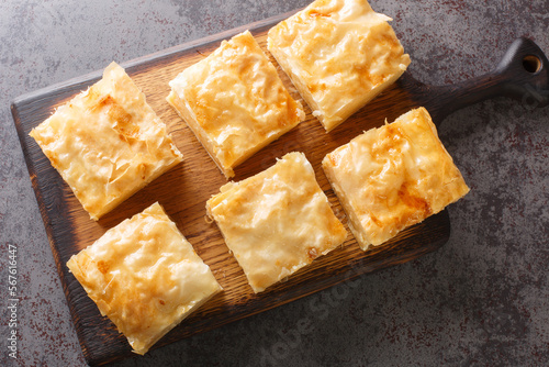 Delicious Greek sweet pastry Galaktoboureko, made of semolina custard in filo closeup on the wooden board on the table. Horizontal top view from above photo