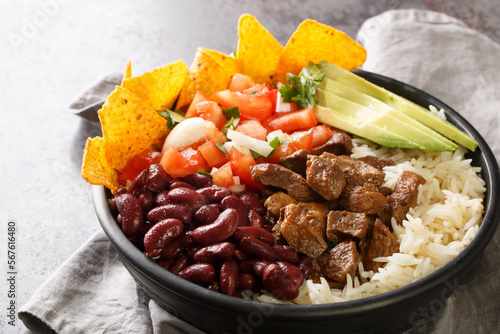 Chifrijo is a delicious traditional Costa Rican dish made with red beans and pork, accompanied by pico de gallo and rice closeup on the plate on the table. Horizontal photo