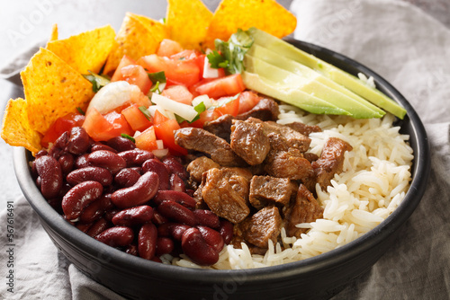Chifrijo is a Costa Rican dish consisting mainly of stewed beans, white rice, pork chicharron and pico de gallo closeup on the plate on the table. Horizontal