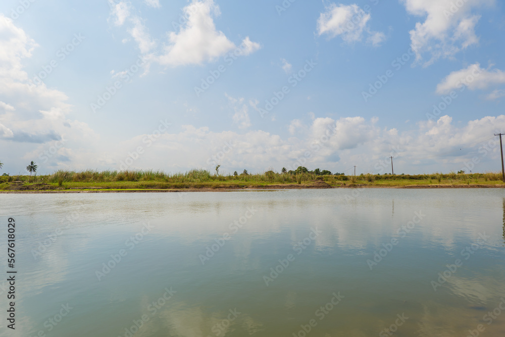 beautiful clouds at the lake in front of agricultural land in the village