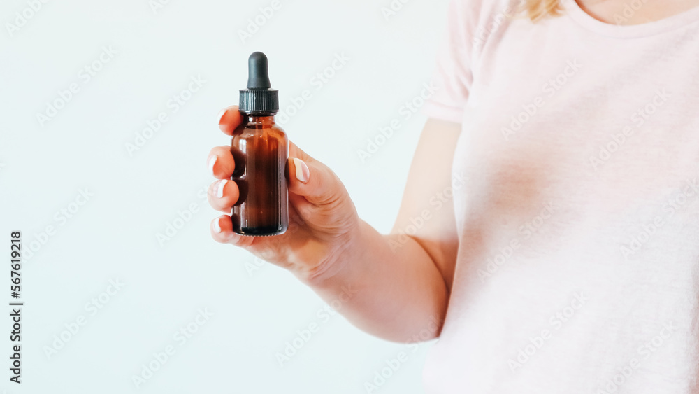 Concept of skin care. Women's hands hold bottle of amber glass with cosmetic serum on white background. Young woman holding brown glass bottle with dropper with spa cosmetics. Concept of skin care. Women's hands hold bottle of amber glass with cosmetic serum on white background. Young woman holding brown glass bottle with dropper with spa cosmetics.