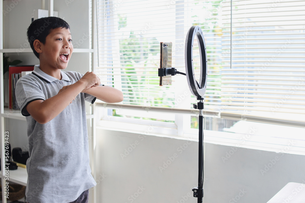 Confident and creative Asian child blogger recording video on digital smartphone. Online influencer boy social media live steaming concept. Confident and creative Asian child blogger recording video on digital smartphone. Online influencer boy social media live steaming concept.