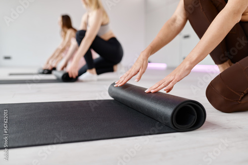 Female fitness group folding mats finished yoga session at sport club