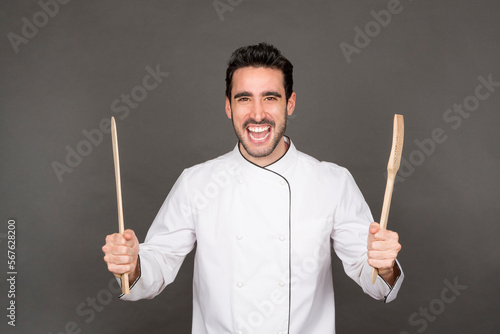 Cook holding up kitchen tools with an expression of happiness