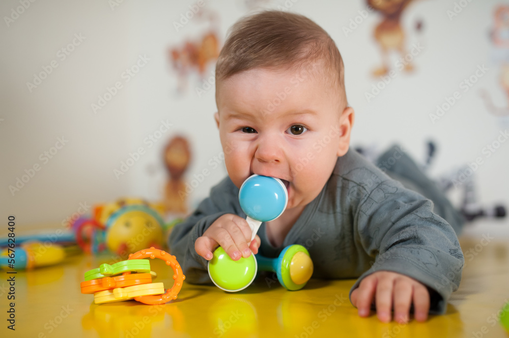 Cute baby boy nibbles and eats colourful toys because her small new teeth grow. Playground for babies Cute baby boy nibbles and eats colourful toys because her small new teeth grow. Playground for babies