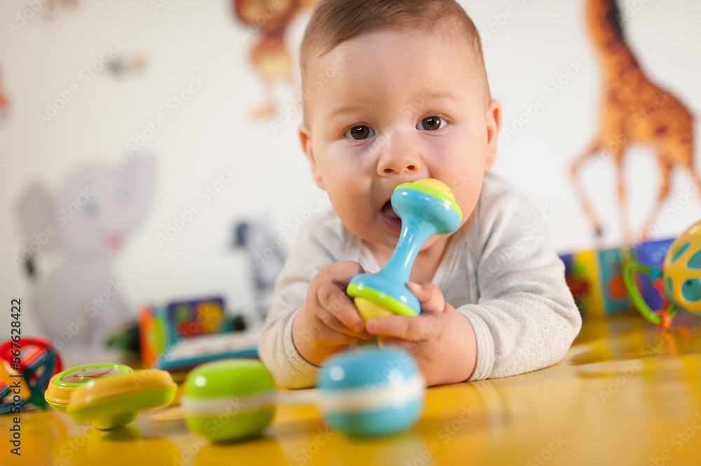Cute baby boy nibbles and eats colourful toys because her small new teeth grow. Playground for babies Cute baby boy nibbles and eats colourful toys because her small new teeth grow. Playground for babies
