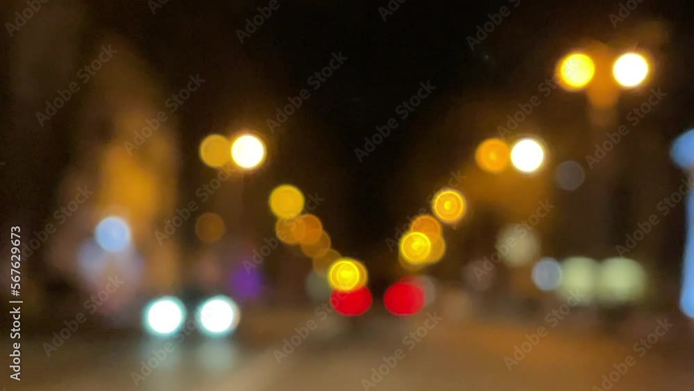 Blurred car lights bokeh in the evening city. Defocused headlights and street lighting at night. Moving bokeh circles of cars at night. Blurred city traffic background Blurred car lights bokeh in the evening city. Defocused headlights and street lighting at night. Moving bokeh circles of cars at night. Blurred city traffic background